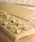 Close-up of Ravioli Maker With Press 12 Inch Mold For Homemade Pasta with fillings, no roller needed, on wooden board.