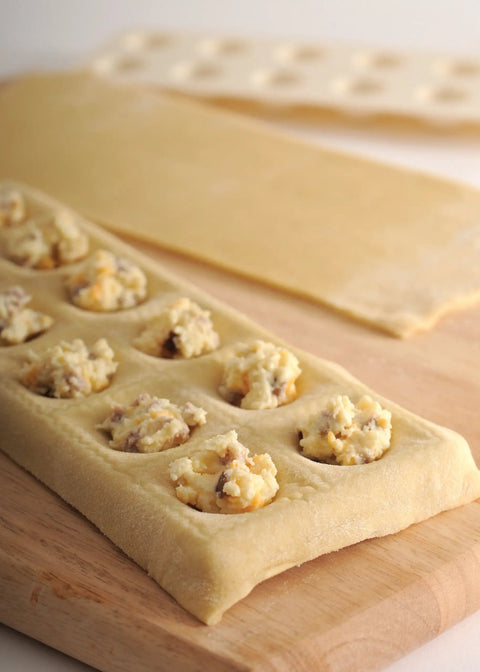 Close-up of Ravioli Maker With Press 12 Inch Mold For Homemade Pasta with fillings, no roller needed, on wooden board.