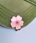 Magnetic Golf Ball Marker Set With Flower Crystal Markers And Hat Clip showing pink flower marker on green hat