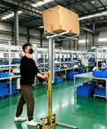 Man operating the Compact Material Lift Stacker With Manual Winch Forklet lifting a cardboard box in a warehouse.