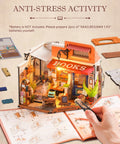 Person assembling DIY Miniature Bookstore Kit 1 To 20 Scale With LED Lights, showing detailed interior and instruction manual.