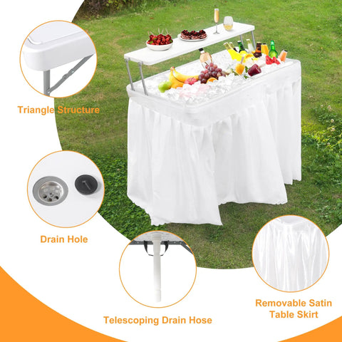 Two Tier Folding Ice Cooler Table With Skirt And Grid Rack Drain Hose Portable Party Table For Patio, Picnic, Camping And Wedding Use Keeps Drinks Cold And Food Fresh White showing features including drain hole and removable satin table skirt on grass