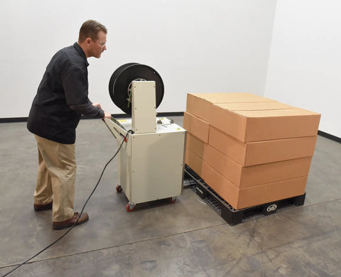 Operator using Heavy Duty Semi Automatic Pallet Strapping Machine Steel Probe Frame 23 X 31.5 X 55 Inches 175 Lb Tension with boxes.