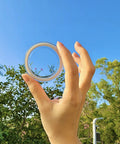 Hand holding Slick Clear Magnetic Base for PopSocket Grips and iPhone MagSafe Cases against a blue sky