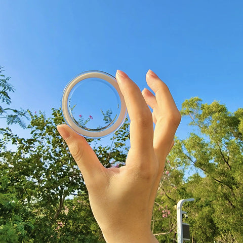 Hand holding Slick Clear Magnetic Base for PopSocket Grips and iPhone MagSafe Cases against a blue sky
