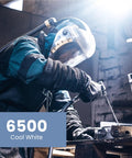 Person welding metal indoors with 6500 Cool White lighting in a workshop setting