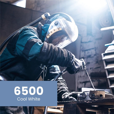 Person welding metal indoors with 6500 Cool White lighting in a workshop setting
