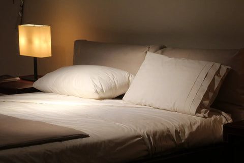 A cozy bedroom setting with a softly lit lamp and neatly arranged pillows on a comfortable bed.