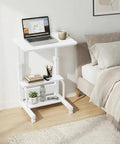 Space Saver C Shaped Laptop Desk On Wheels For Small Spaces White 24 Inch Height Adjustable With 2 Tier Storage Shelves Mobile Under Sofa Or Bed Setup next to a bed with laptop and coffee cup.