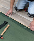 Top Shelf Premium Underlayment One Hundred Square Foot Roll being installed with tools for laminated wood flooring setup.