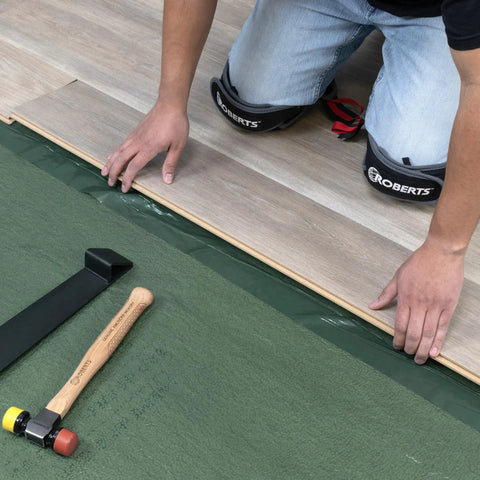 Top Shelf Premium Underlayment One Hundred Square Foot Roll being installed with tools for laminated wood flooring setup.
