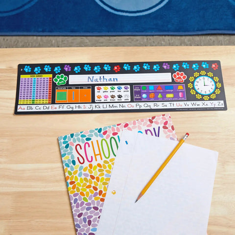 Paw Prints Self Adhesive Deluxe Plastic Desktop Reference Nameplates 24 Pack With Letters Numbers Colors 2D And 3D Shapes 120 Grid Left And Right Base Ten And Time Classroom Learning Tools For The Win on a desk with school books and pencil