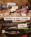 Organized storage of markers, paint brushes, tools, and batteries in clear bins for job ready organization.
