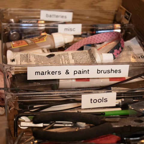 Organized storage of markers, paint brushes, tools, and batteries in clear bins for job ready organization.