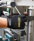 Black General Utility Work Gloves GUG on hand operating machine, showing knuckle protection and secure hook and loop closure