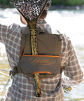 Back view of Cross Current Chest Pack For Fly Fishing Gear, Durable 210D Nylon Cyclepond Fabric, worn by a person by the river