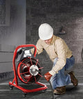 Knockout Heavy Duty Electric Drain Auger With 75 Foot Steel Core Cable in use, clearing kitchen sink clogs by a worker.