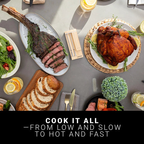 Two Probes Wireless Smart Meat Thermometer For BBQ Oven Grill Smoker And Air Fryer With Two Meats At Once And 1000 Degree Fahrenheit Heat Resistance Long Range Six Sensors And iOS Android App displayed on table with cooked meats and salads.