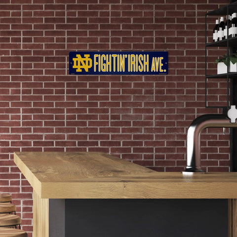 Notre Dame Fighting Irish 16 Inch Plastic Street Sign Wall Decor displayed on a brick wall, perfect for game day and tailgates.