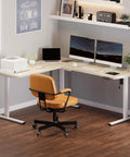Massive 63x47 Inch L-Shaped Electric Standing Desk In Warm Maple Finish with dual monitors and printer setup