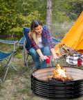 Person enjoying a bonfire in a 60 Inch Extra Large Fire Pit Ring For Outdoors Built Tough And Heavy Duty Wood Burning Pits And Outdoor Fireplaces 12 Inch Tall High Heat Resistant Galvanized Steel Fire Bowl Portable For Backyard Bonfire Patio Camping at campsite