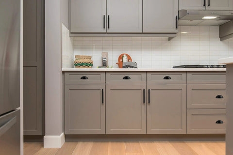 Modern kitchen with flat black cabinet cup pulls 15 pack 3 inch center to center drawer pulls installed on gray cabinets and drawers.