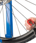 Four Sided Spoke Wrench For Nipples 3.23 Millimeter 0.13 Inch Red Wheel Truing Tool in use on a bicycle rim