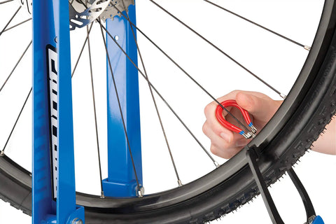Four Sided Spoke Wrench For Nipples 3.23 Millimeter 0.13 Inch Red Wheel Truing Tool in use on a bicycle rim