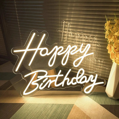 Birthday Neon Sign Led Flex Transparent Acrylic Letter Board Backlight Neon Light For Wall Decor And Party Setup 3D Personalized Neon Signs For Home Bar Room Decor 23.6 x 15.75 Inches Lit Colorful Glow For Party Vibes showing 'Happy Birthday' letters on a floor near a vase.