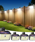 Super Bright 176 Lumen Solar Clip On Fence Lights With Motion Sensor mounted on a wooden fence, illuminating a yard with flowers.