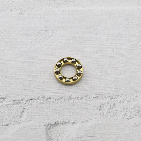 Thrust ball bearing, gold-tone ring with eight chrome steel balls, front view