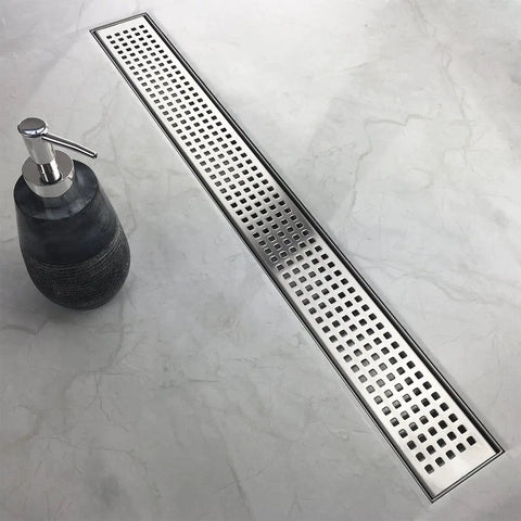 36 Inch Offset Linear Shower Drain With Side Outlet And Quadrato Grate Cover Brushed 304 Stainless Steel in a bathroom setting.