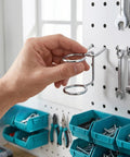 Hand installing a 5 Piece Pegboard Screwdriver Holder Set With Double Ring Tool Organizers For Screwdrivers Pliers Wrenches And Hammers Wall Mount Hooks And Hangers For Easy Access Grab And Go Space Saving Garage Tool Storage on a white pegboard.