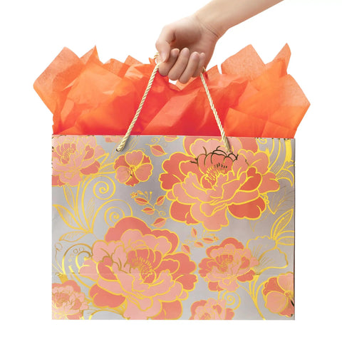 Hand holding Rose Gold Gift Bag Set With Greeting Card And Orange Tissue Paper That Elevates Your Gifting Game, floral design