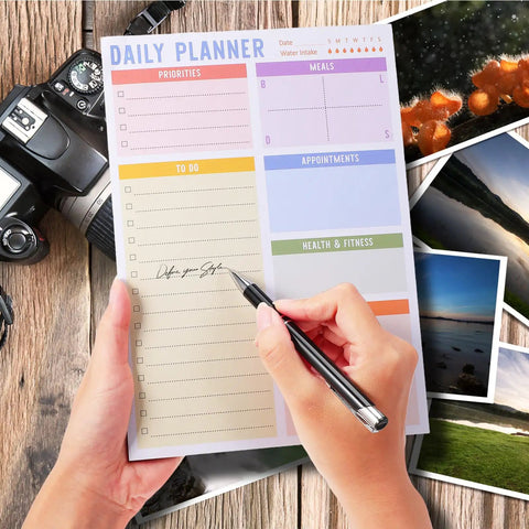Person writing on a daily planner page of a Portable Memo Pad Notebook For Daily Use With No Residue After Tearing.