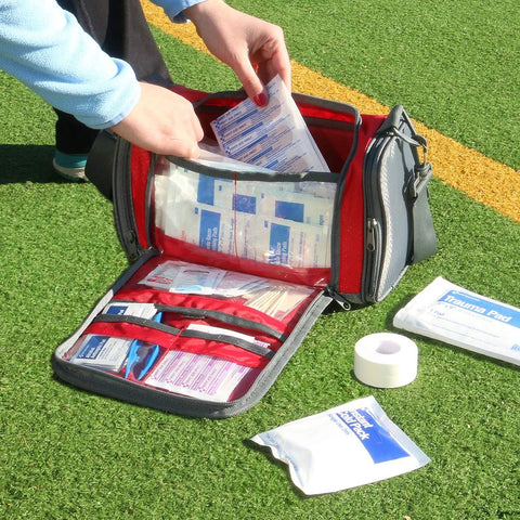 Red and gray duffel-style sports first-aid kit opened on grass, showing 189-piece contents.