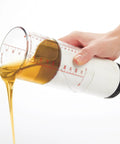Hand using Two Cup Adjustable Measuring Cup with Grippy Rotating Body for Easy Pouring of Peanut Butter and Honey