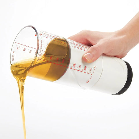 Hand using Two Cup Adjustable Measuring Cup with Grippy Rotating Body for Easy Pouring of Peanut Butter and Honey