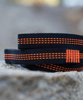 10ft Heavy Duty Hammock Straps for Trees with reinforced stitching, black with orange detail, close-up view on a rock