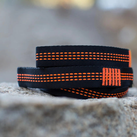10ft Heavy Duty Hammock Straps for Trees with reinforced stitching, black with orange detail, close-up view on a rock
