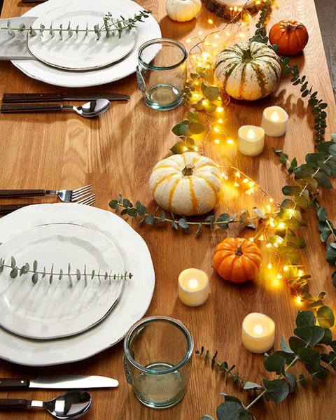 Homemory 24-pack flameless LED tea lights on a wooden table with pumpkins, garland, and string lights
