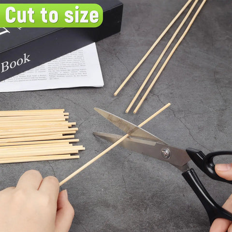 Cutting 150 Piece Smooth Wooden Dowel Rods 1/8 By 12 Inches for DIY crafts with scissors on a gray surface.