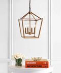 Kickstart Your Space With This Totally Rad Antique Gold 4 Light Pendant Ceiling Fixture Featuring A 12 Inch Caged Lantern Design above a table with books and flowers.