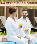 Couple in robes sitting poolside with glasses, Go 4 Portable Bluetooth Speaker with IP67 Waterproof and Dustproof Build visible.