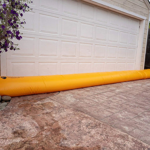 HydraBarrier Supreme Flood Barrier 12 Feet Long 20 Inches Wide 12 Inches High Water Diversion Tube in front of a garage door.