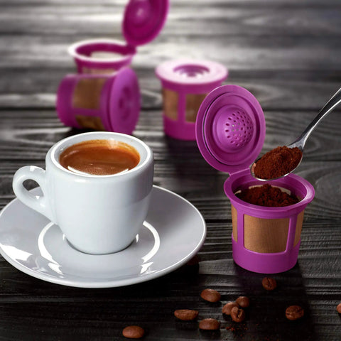 Purple Reusable K Cup Pods For Coffee Nerds Who DIY Their Brews BPA Free Universal Fit For 1.0 And 2.0 Brewers next to a coffee cup
