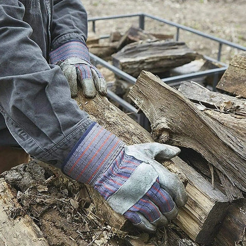Person stacking firewood wearing heavy duty work gloves for landscaping and gardening, 12 pair pack with safety cuff and wing thumb.