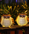 Two Pack Hanging Solar Lanterns With Owl Pattern Waterproof Metal Outdoor Garden Lights illuminating a garden pathway.