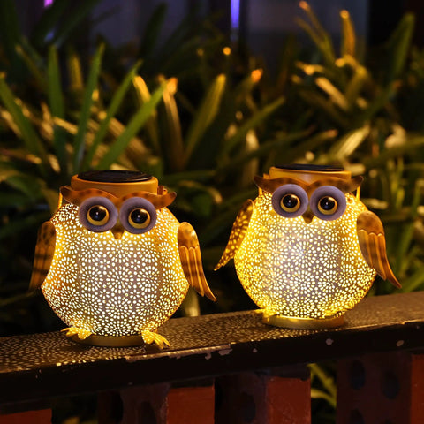 Two Pack Hanging Solar Lanterns With Owl Pattern Waterproof Metal Outdoor Garden Lights illuminating a garden pathway.