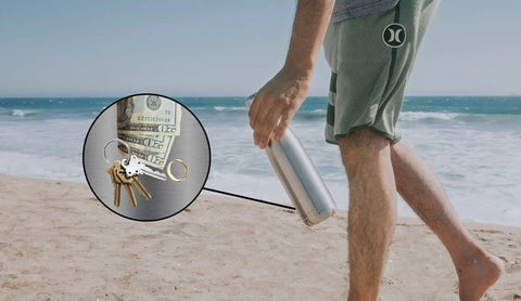 Person holding Hidden Compartment Stainless Steel Water Bottle Safe Tumbler With Secret Bottom Stash on a beach with valuables inside
